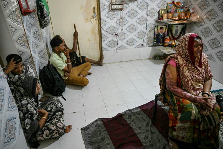 Sita Patni (d), qui a été brûlée et a perdu son fils Akash Patni dans le crash du vol 171 d'Air India,  entourée de ses proches lors d'un entretien avec l'AFP à son domicile à Ahmedabad, le 8 novembre 2025 en Inde 