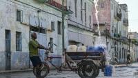 Un homme remplit des récipients d'eau à un point de ravitaillement public dans une rue de La Havane, le 5 octobre 2026