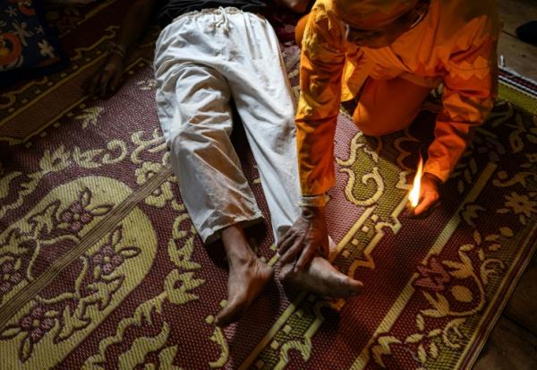 Photo fournie par Luke Duggleby, prise le 10 décembre 2025 et transmise à l'AFP le 25 février 2026, montrant le chef religieux Jaha Satae (c,d), procédant à une cérémonie de purification sur Jawa Jabo (chemise noire), dans le village de Mae Haeng, à Chiang Mai, en Thaïlande