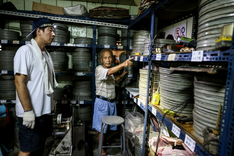 Le collectionneur Wang Chin-ting (D) montre des bobines de vieux films taïwanais à un membre de l'Institut taïwanais du cinéma et de l'audiovisuel (TFAI), le 29 mai 2026 à Changhua, dans la province de Taïwan