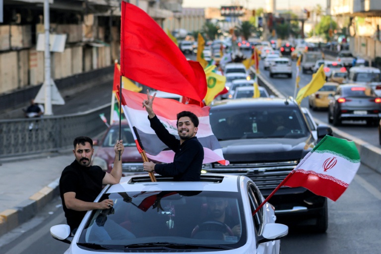 Des jeunes circulent en véhicules en brandissant des drapeaux irakiens, iraniens, libanais et du Hezbollah, lors des célébrations qui ont suivi l'annonce d'un accord mettant fin à la guerre entre l'Iran et les États-Unis, le 15 juin 2026 à Bagdad