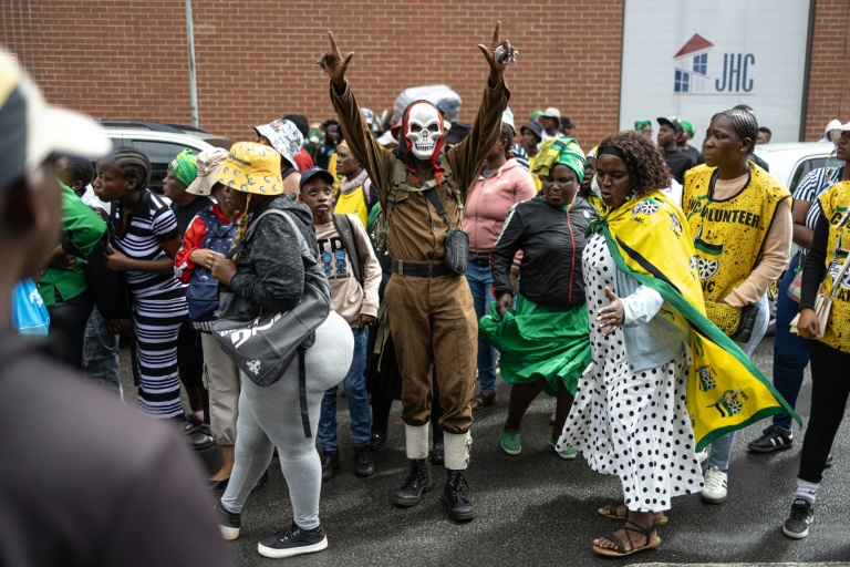 Un manifestant masqué réagit lors d'une manifestation de l'ANC à Johannesburg le 21 mars 2026.