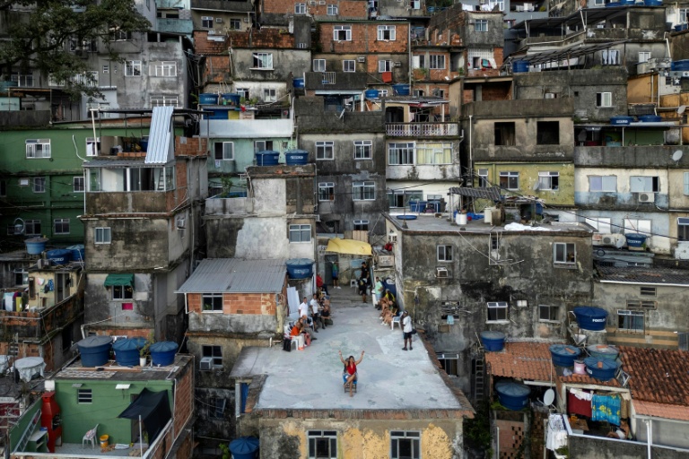 Vue aérienne d'une touriste se faisant filmer par un drone sur le toit d'une maison dans la favela de Rocinha, à Rio de Janeiro, au Brésil, le 5 mars 2026