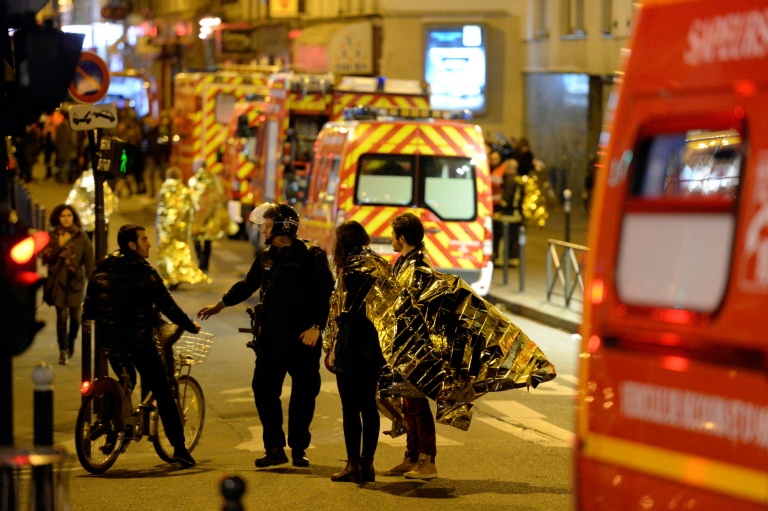 Des personnes rue Oberkampf, près de la salle de concert du Bataclan ciblée par une attaque jihadiste meurtrière, sont évacuées par les forces de police dans la nuit du 13 au 14 novembre 2015 à Paris