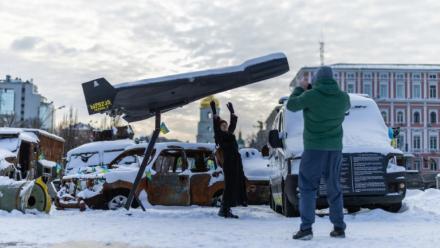 Une femme pose sur fond d'un drone russe Shahed abattu et exposé à Kiev, le 17 février 2026 