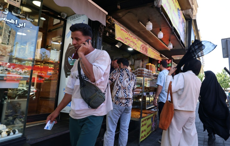 Un Iranien parle au téléphone dans une rue de Téhéran le 25 mai 2026