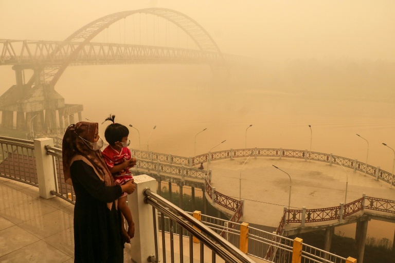 Une mère et son enfant dans la fumée provoquée par les incendies, le 12 octobre 2026 à Palangkaraya, en Indonésie