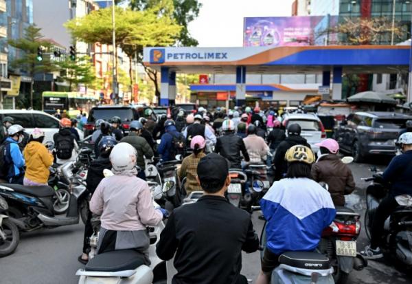 Des motocyclistes font la queue pour faire le plein d'essence dans une station-service à Hanoï, le 10 mars 2026 au Vietnam