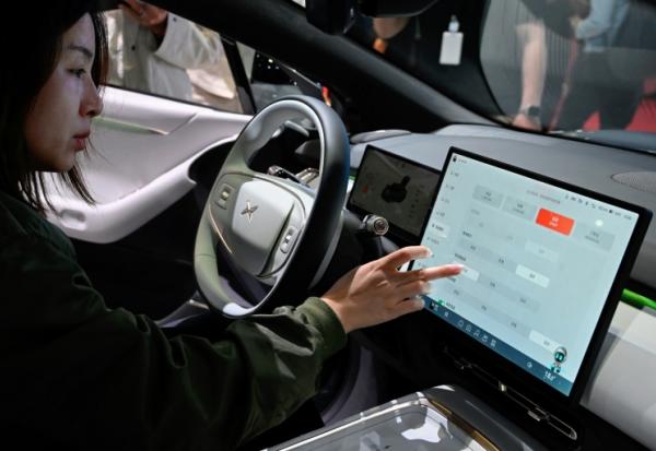 Une visiteuse découvre l'habitacle d'un véhicule P6 de Xpeng lors du salon automobile de Shanghai, le 25 avril 2025