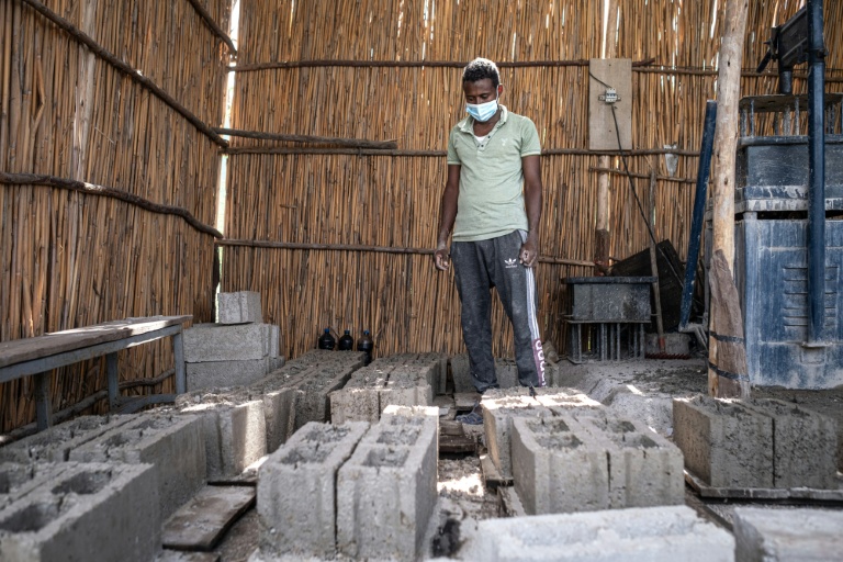 Un employé examine des briques fabriquées à partir de prosopis dans l'un des petits centres de transformation gérés avec le soutien de l'ONG CARE dans le woreda d'Amibara, le 16 octobre 2025 dans la région de l'Afar, en Ethiopie