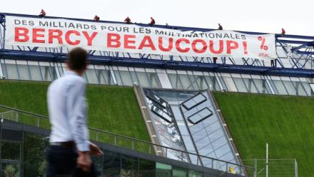 Des militants de l'organisation Attac France déploient une banderole sur la salle de spectacles Accor Arena à Paris mardi 2 juin 2026, protestant contre les aides publiques aux multinatinales 