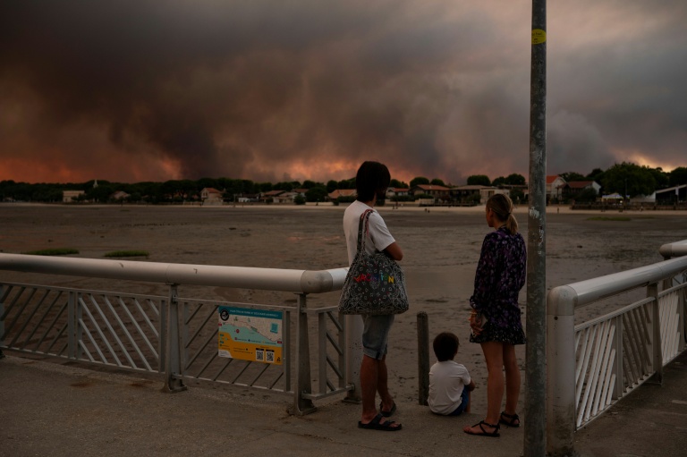 Des gens regardent les fumées d'un incendie à Lège-Cap-Ferret depuis la plage d'Andernos-les-Bains, en Gironde, le 23 juillet 2026

