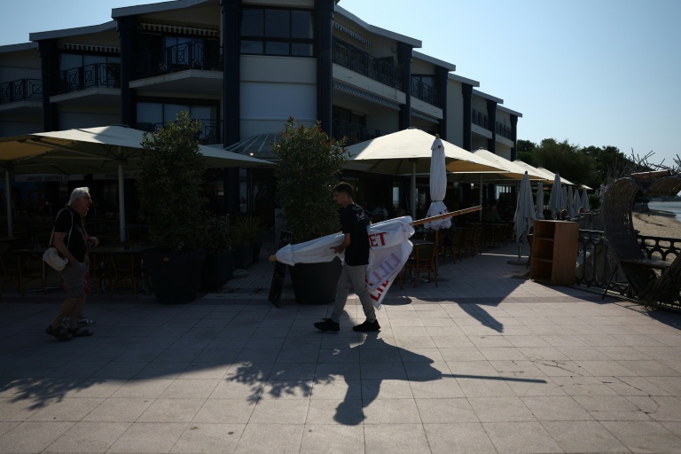 Un employé de restaurant transporte un parasol à Andernos-les-Bains, en Gironde, le 1er août 2026