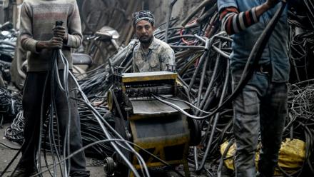 Des hommes récupérant de l'aluminium de fils plastiques dans un centre informel de recyclage de Seelampur, à New Delhi en Inde, le 28 janvier 2026