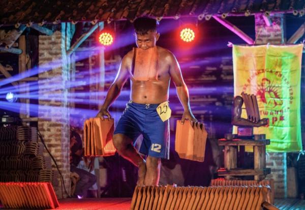 Un ouvrier indonésien porte des tuiles lors d'un concours de culturisme le 11 août 2025 à Jatiwangi