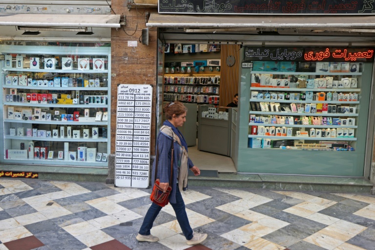 Une Iranienne passe devant une boutique de téléphonie mobile, le 19 avril 2026 à Téhéran