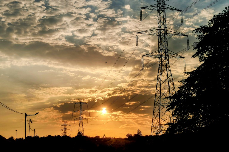 Des pylônes électriques à haute tension au coucher du soleil, dans l'ouest de Téhéran, le 2 août 2022