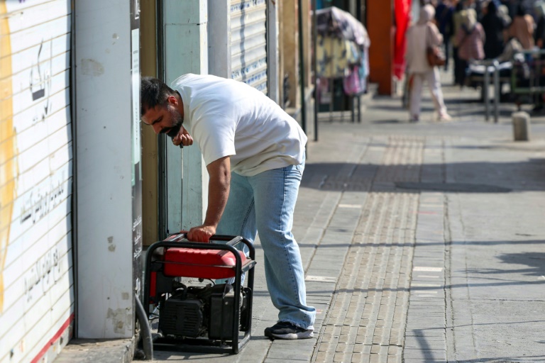 Un homme démarre un générateur pour alimenter son magasin lors d'une à Téhéran, le 1er septembre 2025 en Iran