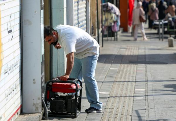 Un homme démarre un générateur pour alimenter son magasin lors d'une à Téhéran, le 1er septembre 2025 en Iran