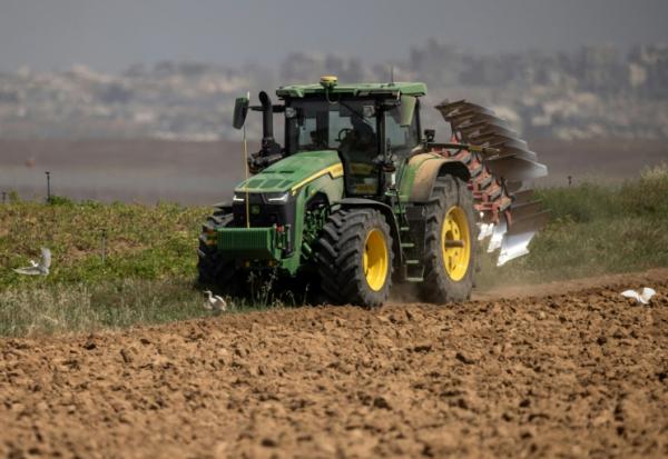Un agriculteur en tracteur dans un champ agricole près de la frontière entre le sud d'Israël et la bande de Gaza, le 21 mai 2025