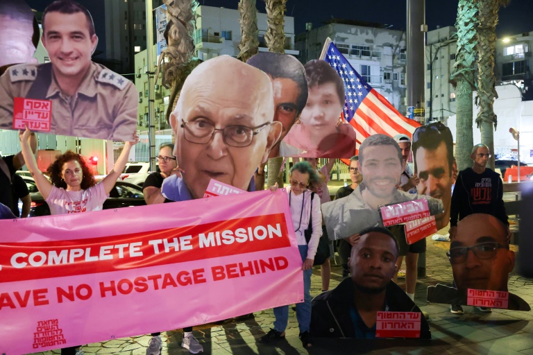 Des Israéliens brandissent des portraits d'otages décédés toujours retenus par le Hamas dans la bande de Gaza, lors d'un rassemblement devant l'antenne de l'ambassade américaine à Tel-Aviv, le 21 octobre 2025