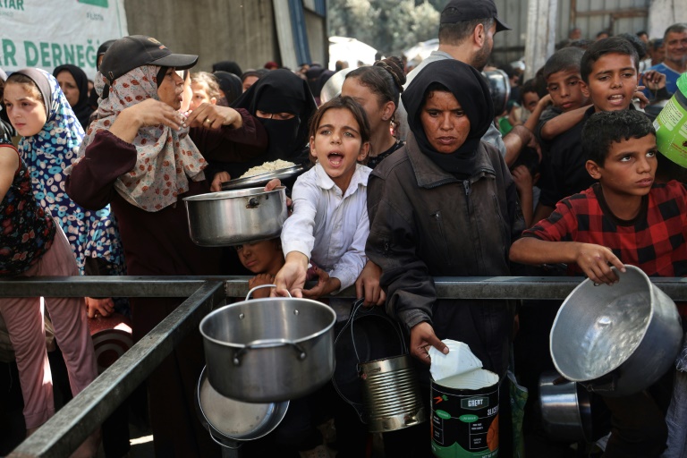 Des Palestiniens se rassemblent pour recevoir des portions alimentaires distribuées par une cuisine caritative dans le camp de réfugiés de Nousseirat, dans le centre de la bande de Gaza, le 15 octobre 2025

