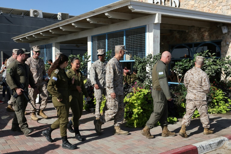 Des soldats américains et israéliens marchent dans une rue près du kibboutz de Kfar Aza,dans le sud d'Israël près de la frontière avec Gaza, le 21 octobre 2025