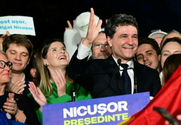 Le maire de Bucarest et candidat à la présidence roumaine, Nicusor Dan, salue ses partisans à l'annonce des sondages de sortie des urnes, le 18 mai 2025 à Bucarest