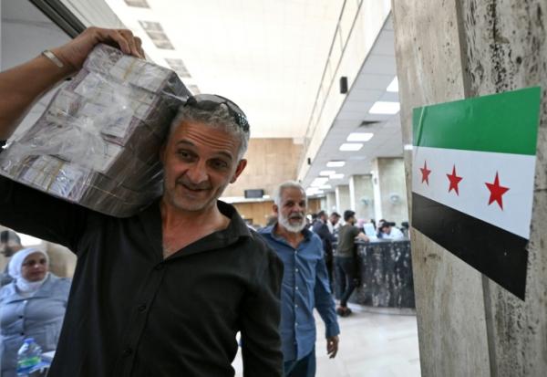 Un homme quitte la banque centrale de Damas avec des livres syriennes, le 21 mai 2025

