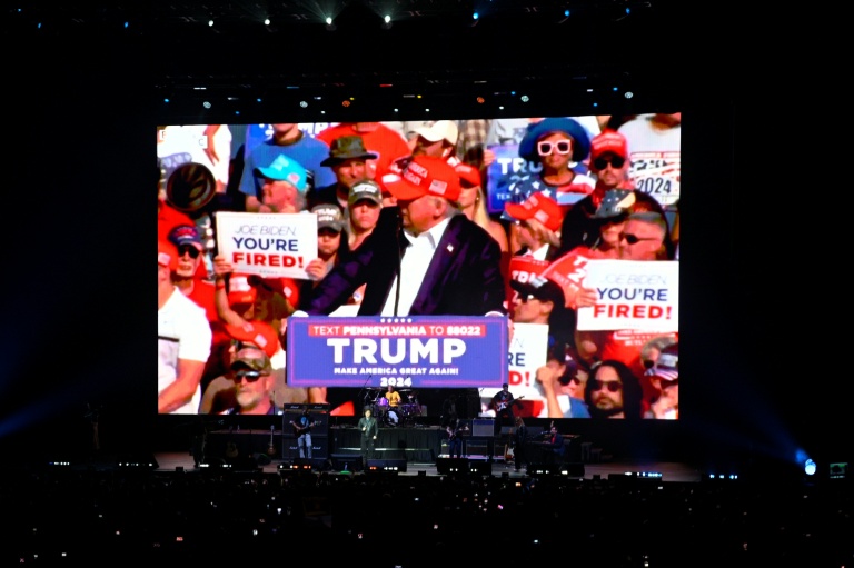 Le président argentin Javier Milei sur scène alors que des images du président américain Donald Trump sont projetées sur un écran géant lors du lancement de son nouveau livre, 