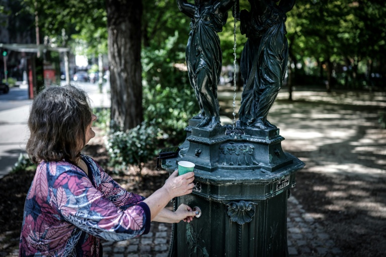 Une femme remplit un gobelet d'eau à une fontaine publique du quartier Montparnasse, le 25 mai 2026 alors que Météo-France a placé la capitale en alerte jaune face à une vague de chaleur exceptionnellement précoce