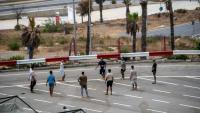 Des migrants jouent au foot sur un parking près d'abris temporaires installés pour eux, le 27 août 2026 à Ceuta