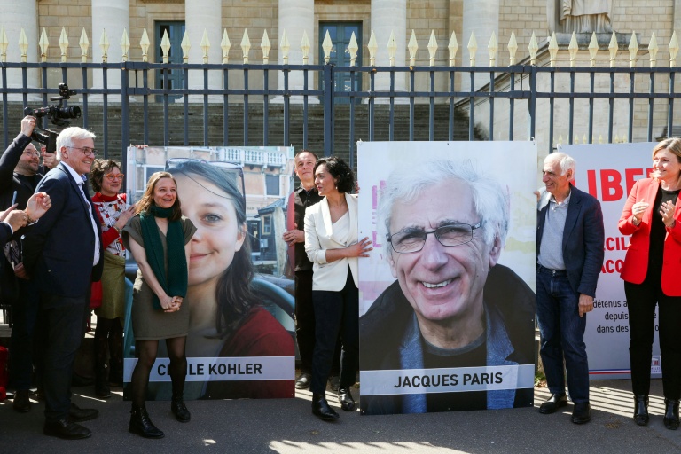 Cécile Kohler (3e G) et Jacques Paris (2e D) devant leurs portraits décrochés des grilles de l'Assemblée nationale, à Paris le 14 avril 2026