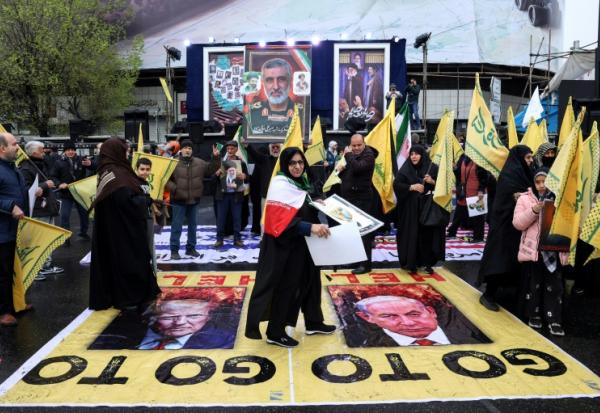 Des Iraniennes piétinent les portraits du président américain Donald Trump (g) et du Premier ministre israélien Benjmin Netanyahu, lors de la Journée de Qods, en solidarité avec les Palestiniens, à Téhéran, le 13 mars 2026 en Iran