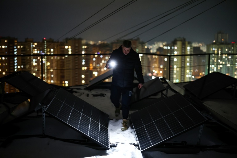 Un homme inspecte des panneaux solaires, le 22 février 2026, à Kiev, à la suite de coupures d'électricité