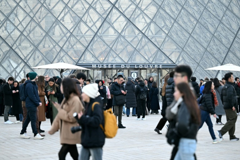 Des visiteurs devant la pyramide du Louvre le 15 décembre 2025 à Paris