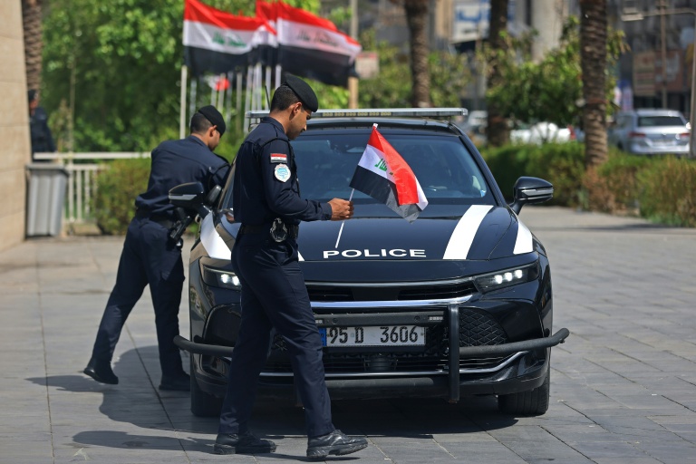 Des policiers placent des drapeaux iraquiens sur leur véhicule à Bagdad le 29 septembre 2026