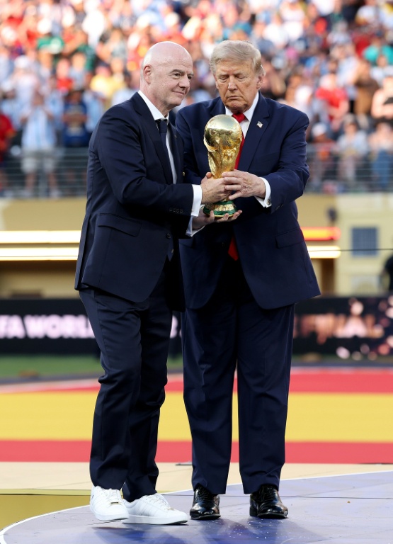 Le président de la Fifa Gianni Infantino (à gauche) et le président américain Donald Trump tiennent le trophée de la Coupe du monde 2026 avant de le remettre à l'Espagne, championne du monde le 19 juillet 2026 à East Rutherford (Etats-UNis)

