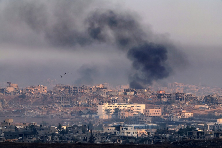 Photo prise depuis le côté israélien de la frontière avec la bande de Gaza montrant de la fumée s’élevant au-dessus de bâtiments détruits, lors d’un bombardement israélien dans le territoire palestinien assiégé, le 22 mai 2025