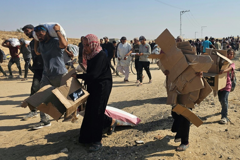 Des Palestiniens déplacés marchent le long d'une route pour recevoir des colis d'aide humanitaire d'un centre d'aide soutenu par les États-Unis à Rafah, dans le sud de la bande de Gaza, le 5 juin 2025