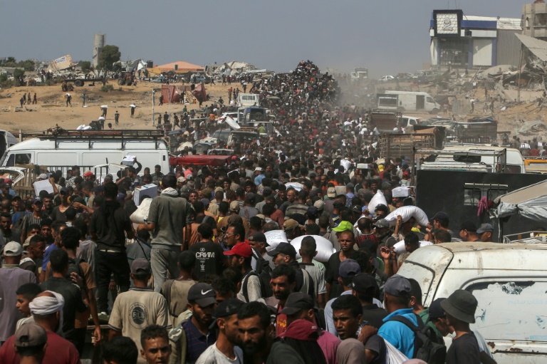 Des Palestiniens déplacés portant des sacs de vivres après une ruée sur des camions transportant de l'aide à Khan Younès, dans le sud de la bande de Gaza, le 9 août 2025