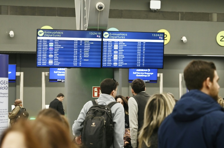 Des passagers devant un panneau d'information affichant de nombreux vols annulés, à l'aéroport de Thessalonique en Grèce le 4 janvier 2026