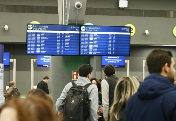 Des passagers devant un panneau d'information affichant de nombreux vols annulés, à l'aéroport de Thessalonique en Grèce le 4 janvier 2026
