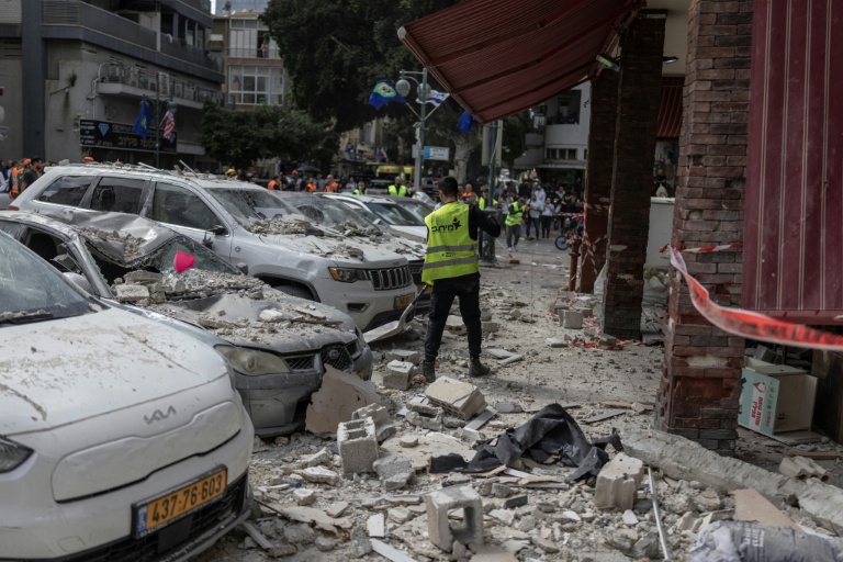 Des employés municipaux nettoient la rue devant un bâtiment touché par une attaque iranienne à Ramat Gan, dans le centre d'Israël, le 6 avril 2026