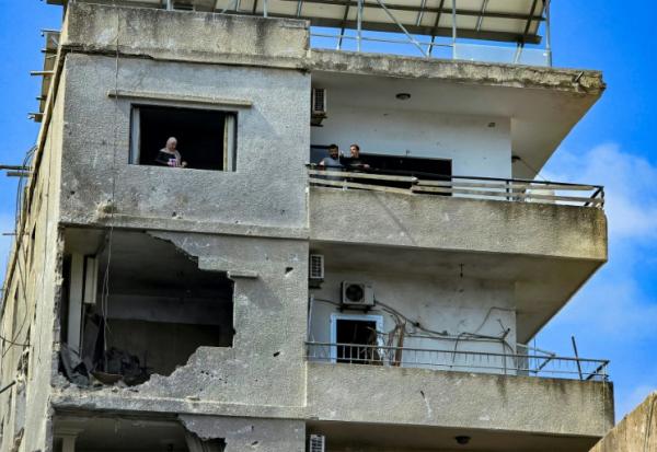 Des habitants dans un immeuble endommagé par une frappe israélienne octurne à Tyr, dans le sud du Liban, le 16 mai 2026
