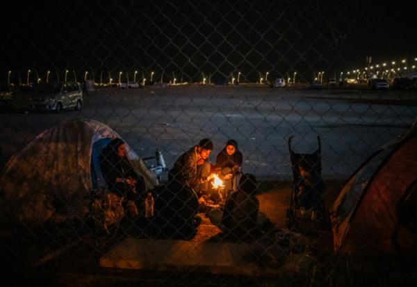 Une famille de déplacés se réchauffe devant une tente sur le front de mer de Beyrouth le 18 mars 2026