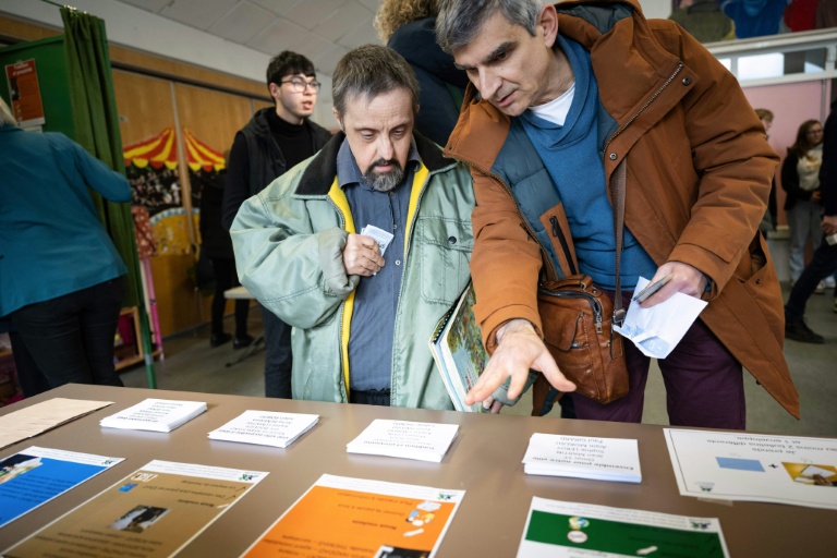 Un éducateur explique les règles pour voter lors d'un faux scrutin organisé pour des personnes en situation de handicap intellectuel, le 17 février 2026 à  Saint-Dié-des-Vosges