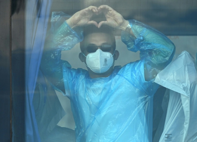 Un passager du navire de croisière MV Hondius, touché par un foyer d'hantavirus, fait un signe depuis un bus militaire après avoir débarqué dans le port de Granadilla de Abona, sur l'île de Ténérife, dans les îles Canaries (Espagne), le 11 mai 2026