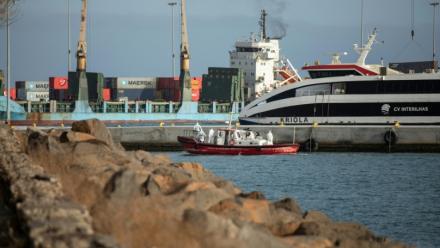 Un bateau-ambulance transportant des membres d'équipage en combinaisons de protection  retourne au port de Praia, après une visite à bord du bateau de croisière MV Hondius, au mouillage au large du port, le 5 mai 2026 au Cap-Vert