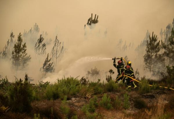 Des pompiers arrosent la lisière d'une forêt lors d'un incendie de forêt près de la ville de Lège-Cap-Ferret, en Gironde, le 25 juillet 2026